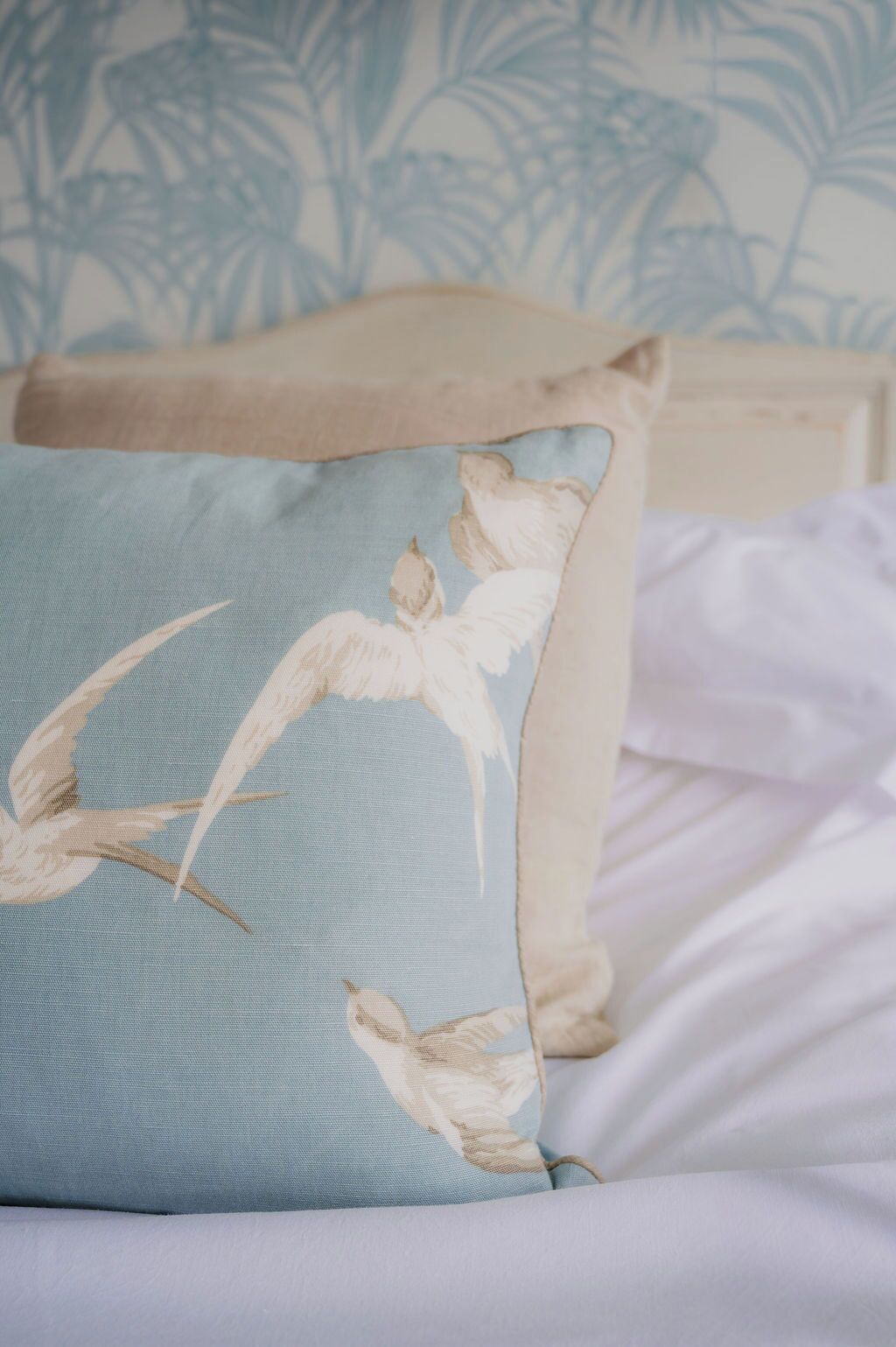 A pillow with a bird design on a bed.