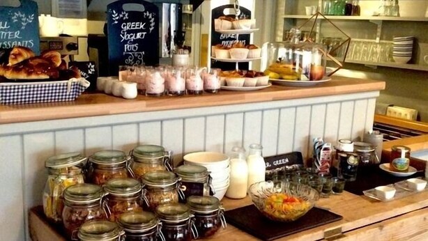 A bakery counter with jars of preserves, pastries, and a chalkboard menu. - The Beach House (Chichester)