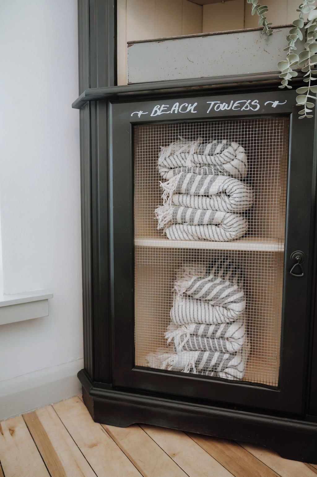 A display case with the text 'BEACH TOWELS' and two shelves of striped towels.