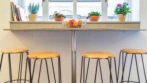 A kitchen counter with a fruit bowl, potted plants, and three wooden stools. - Luxury London Apartment 5-double rooms (London)