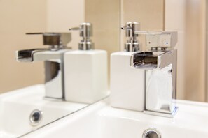A modern bathroom with chrome fixtures and a mirror.
