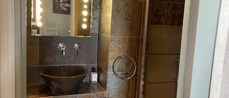 A bathroom with a large mirror, vanity, and a shower area.
