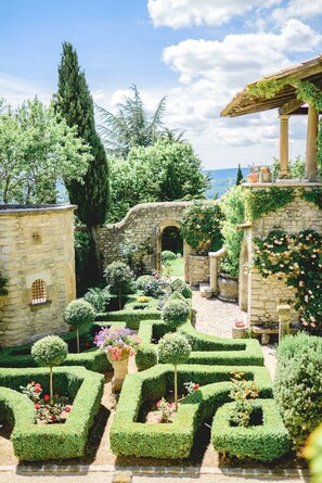 A garden with stone walls, a pergola, and neatly trimmed hedges. - La Lauren (Ferrassières)