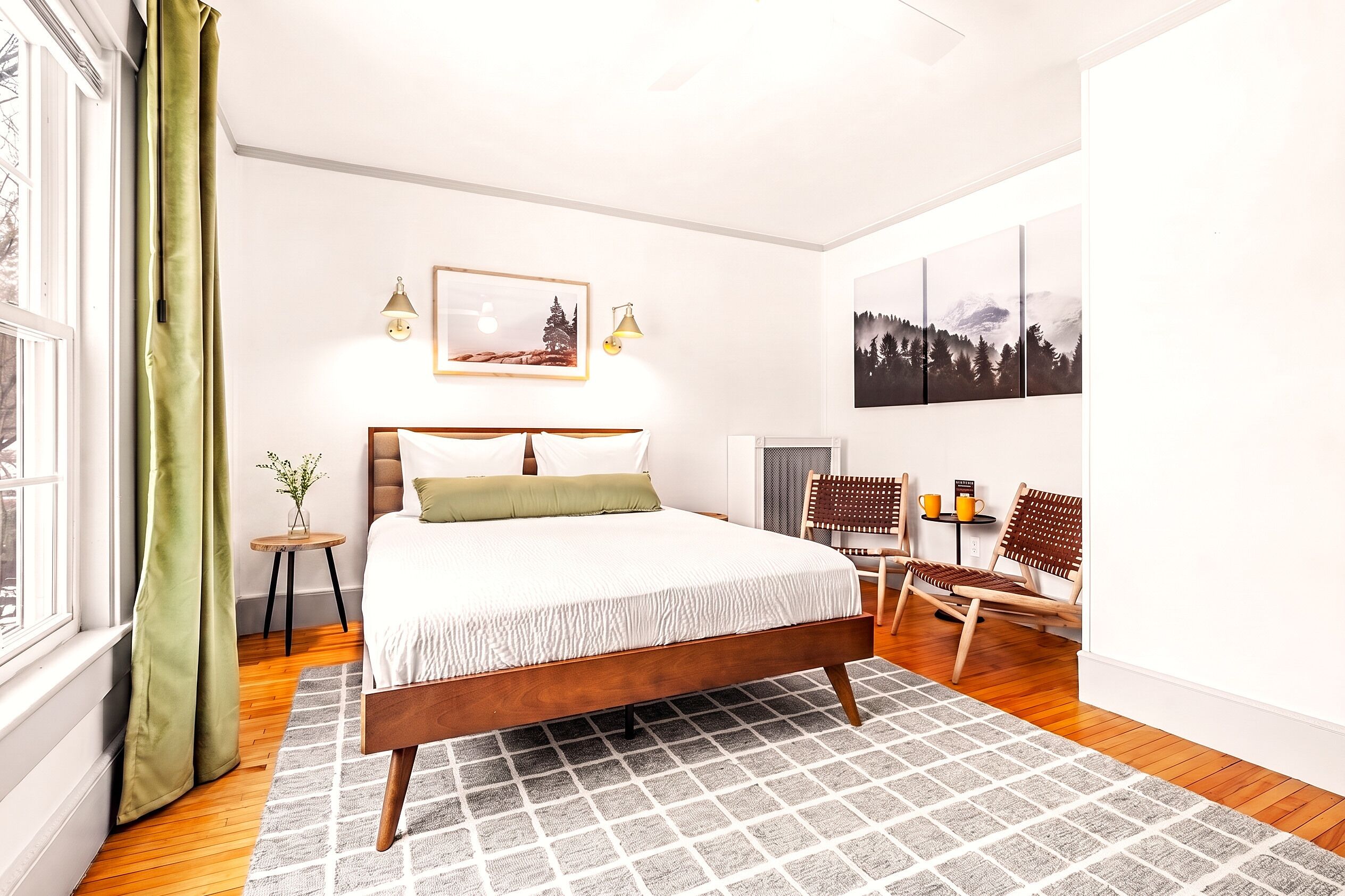 A bedroom with a bed, a small table with a plant, and a chair.