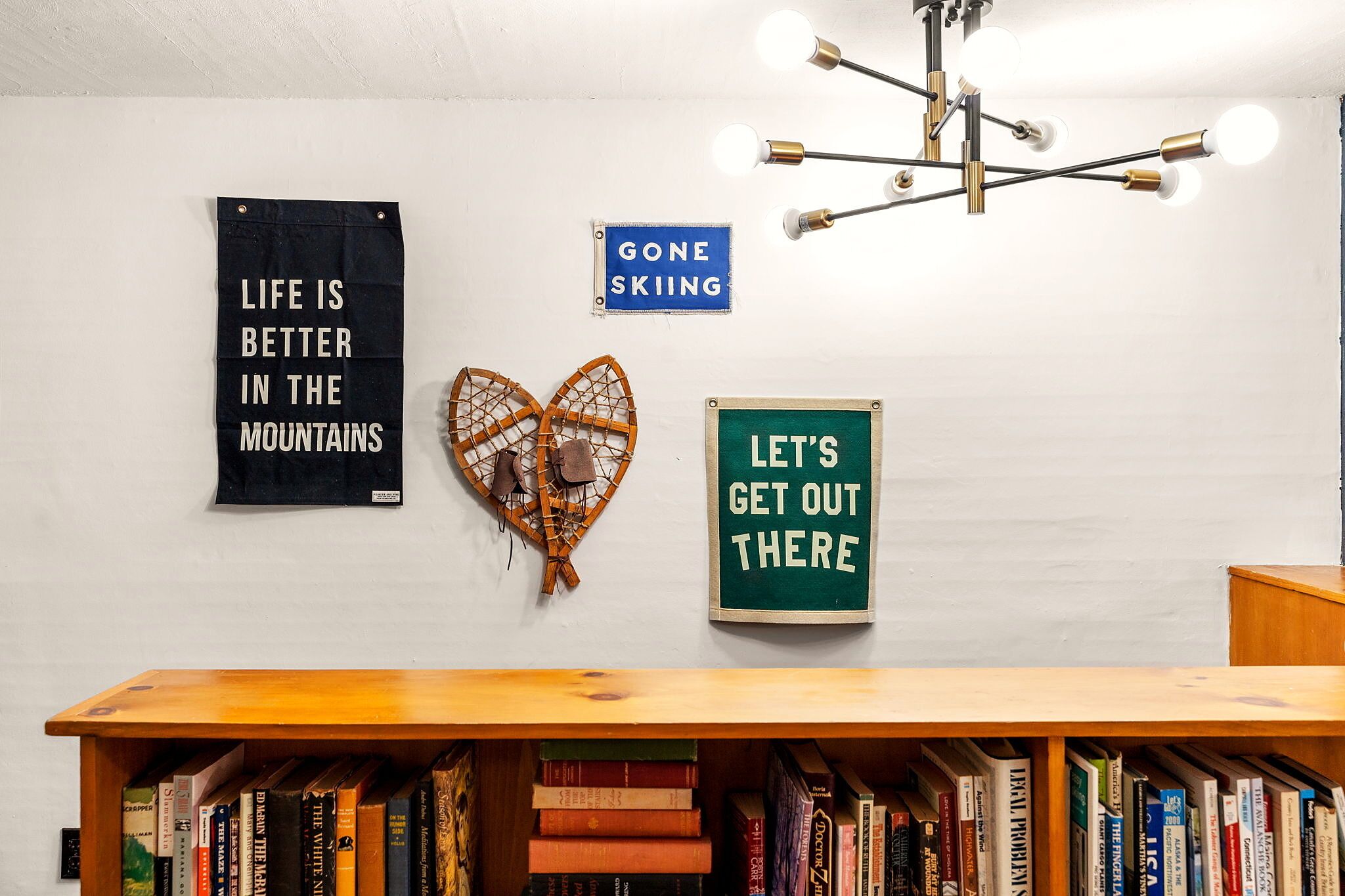 A bookshelf filled with books, a wall with motivational signs, and a ceiling light fixture.