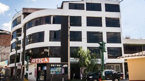 A multi-story building with a commercial ground floor featuring a pharmacy and a coffee shop. - Yuyay Apartaments Cusco (Cusco)