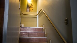 A staircase with a handrail, a light fixture above, and a door at the bottom. - Yuyay Apartaments Cusco (Cusco)