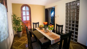 A dining area with a wooden table, chairs, a potted plant, and a vase with flowers. - Yuyay Apartaments Cusco (Cusco)
