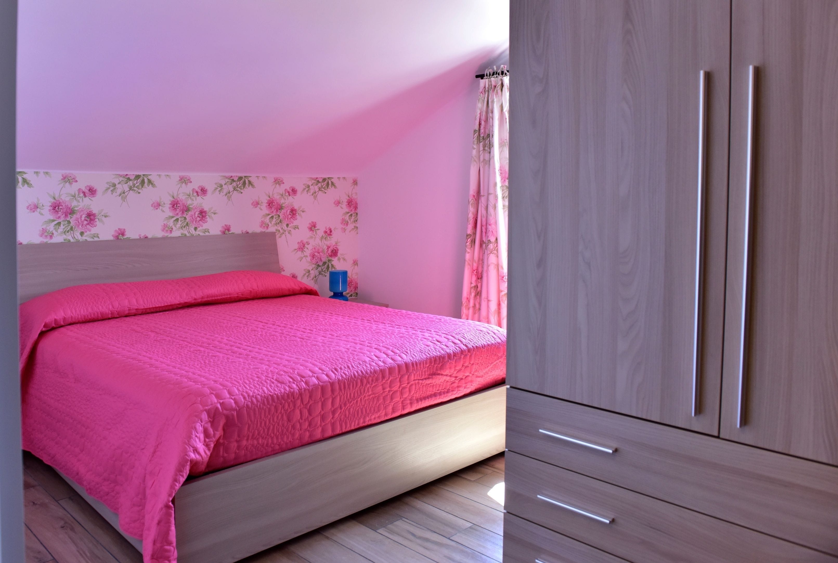 Une chambre à coucher avec un lit, une armoire et un papier peint à motifs floraux.
