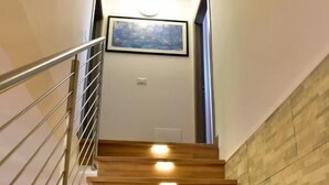 Una escalera de madera con barandillas metálicas que lleva a un rellano con un cuadro enmarco.