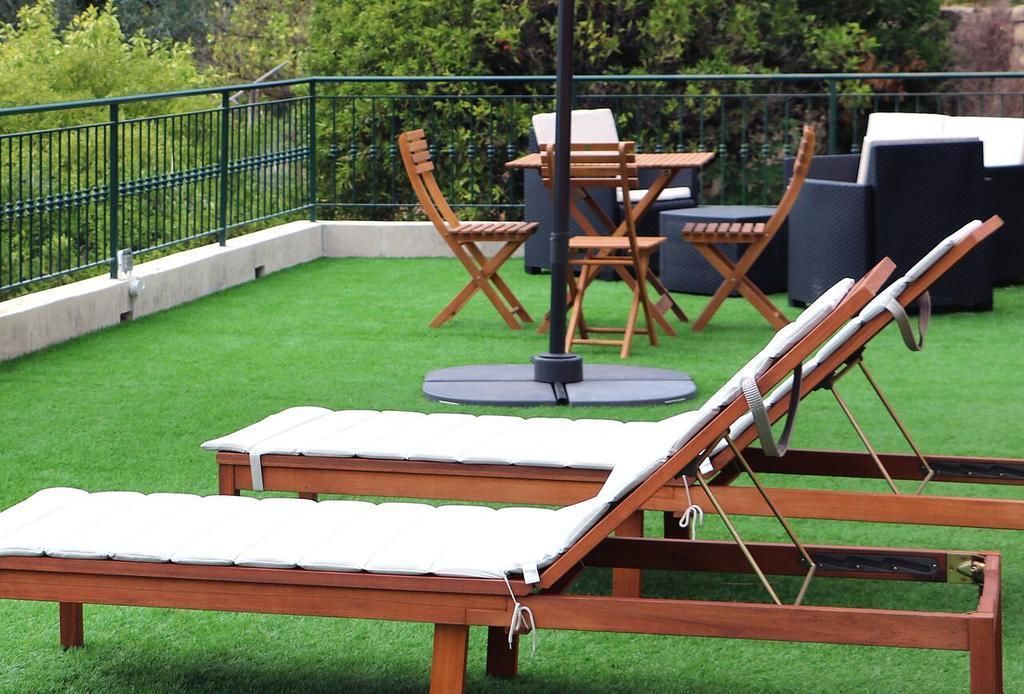 Une terrasse sur le toit avec un fauteuil de relaxation en bois, une table et des chaises.