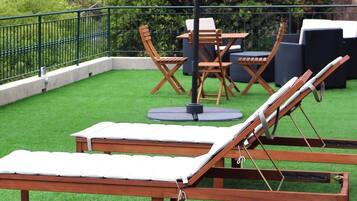 Une terrasse sur le toit avec un fauteuil de relaxation en bois, une table et des chaises.