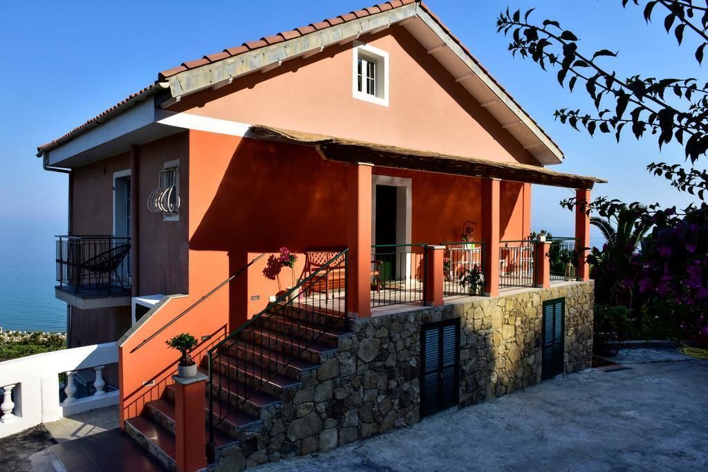 Un edificio a due piani con facciata in pietra, un balcone e vista mare.