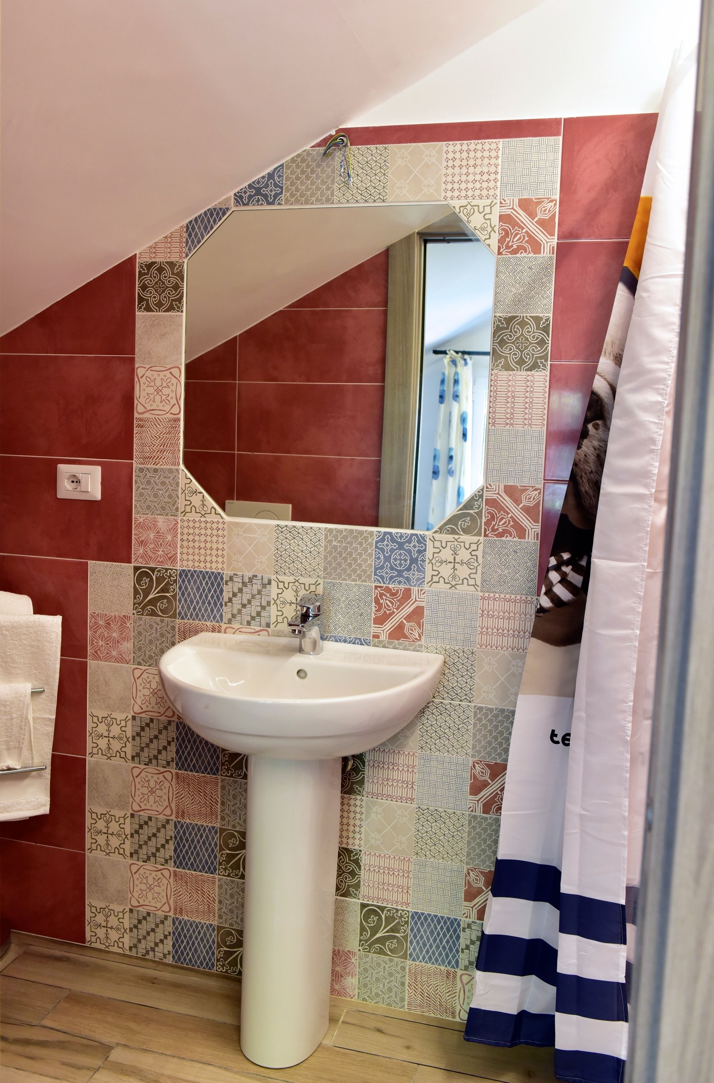 A bathroom with a sink, mirror, and patterned tiles.