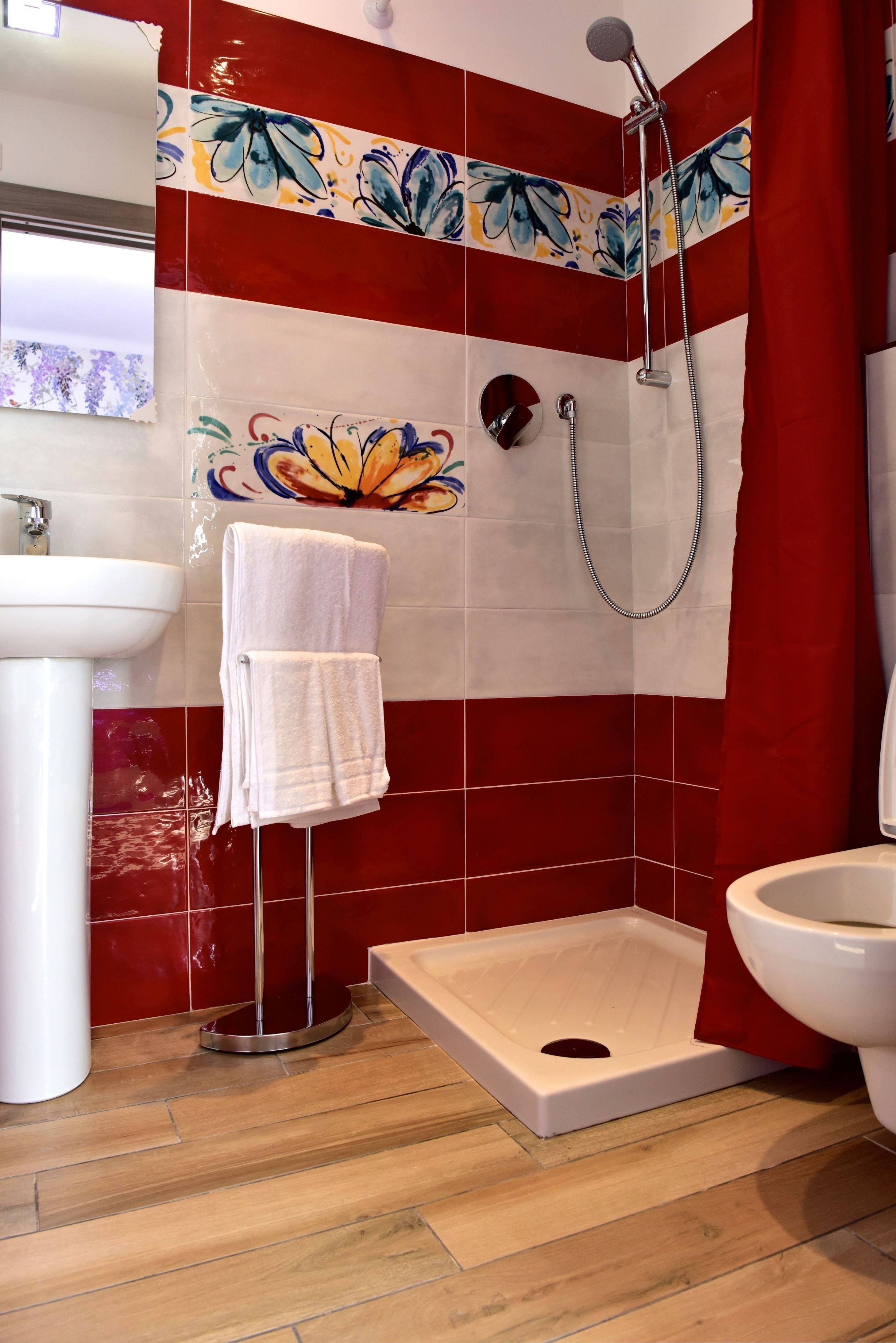 Un bagno con piastrelle rosse e bianche, una doccia, un water e un lavandino.