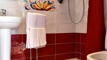 Un bagno con piastrelle rosse e bianche, una doccia, un water e un lavandino.