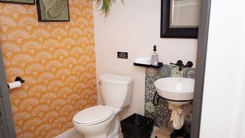 Une salle de bain équipée de toilettes, d’un lavabo et d’une poubelle.