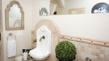 Une salle de bain équipée d’un lavabo, d’un miroir, d’un porte-serviettes et d’une plante en pot.