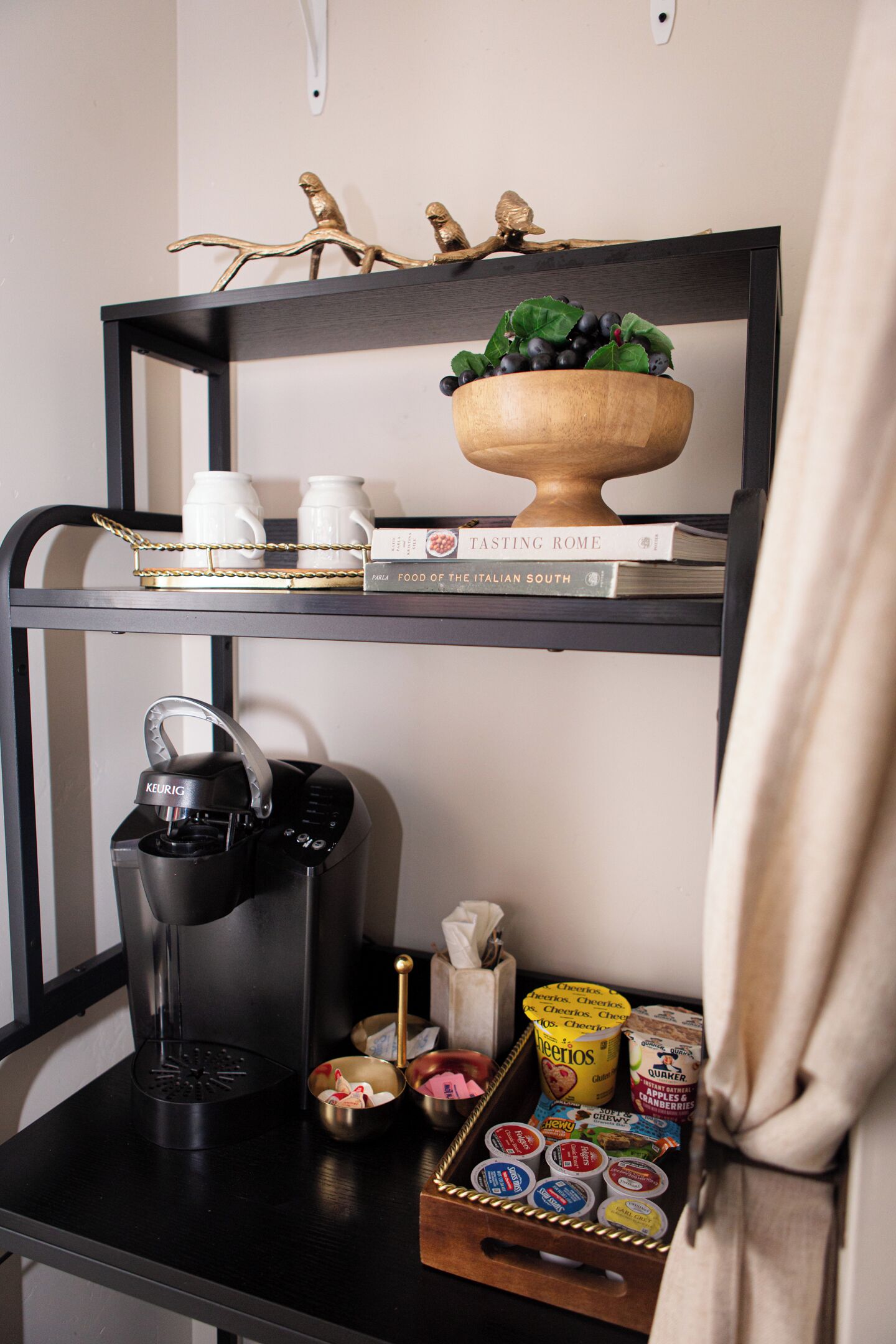 A kitchen counter with a coffee maker, a bowl of fruit, and a tray of yogurt cups.