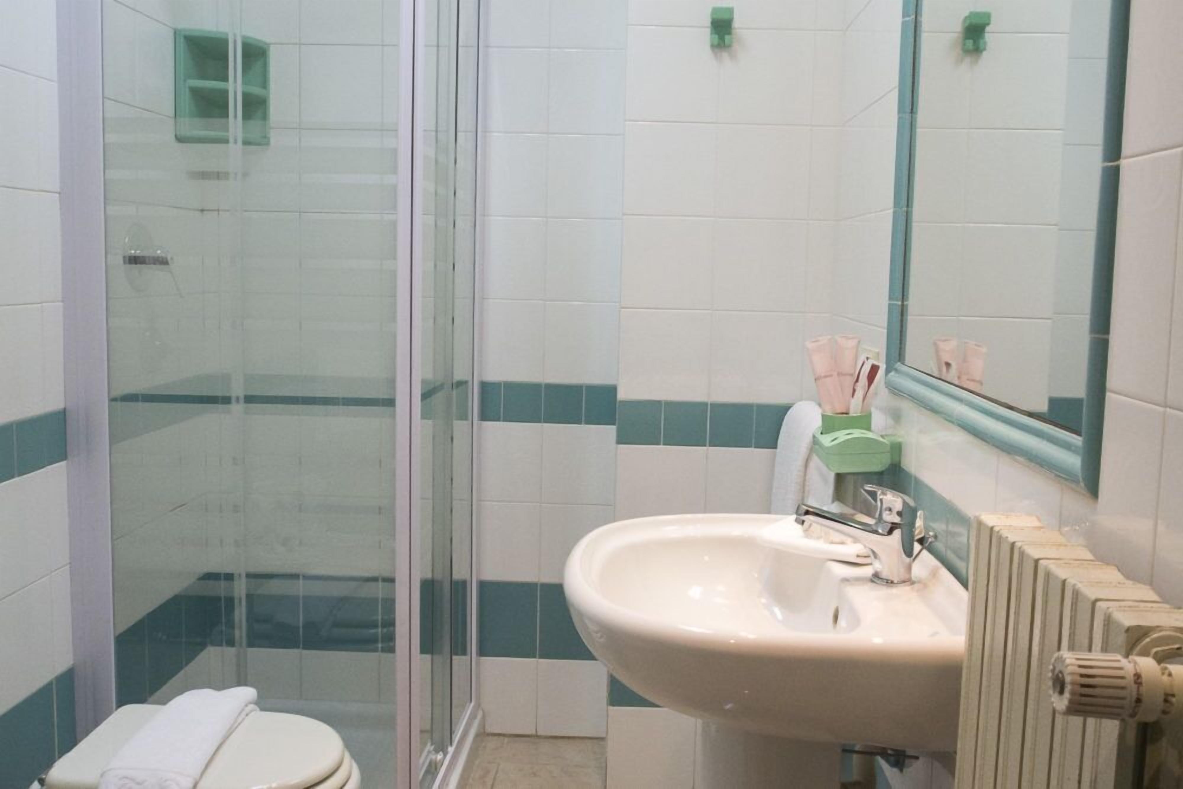 Un baño con cabina de ducha de vidrio, lavabo con espejo e inodoro.