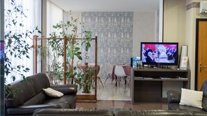 A living room with two leather sofas, a television, and a potted plant. - Hotel Kroma (Ragusa)