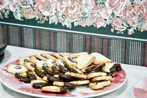 Un plato de galletas y pasteles varios sobre una mesa con un fondo de papel tapiz floral.