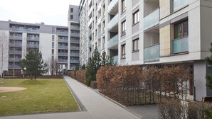 Een modern appartementencomplex met meerdere balkons, een geplaveid pad en een klein stukje gras.