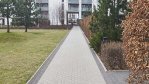 Een pad dat leidt naar een modern appartementencomplex met meerdere verdiepingen en balkons.