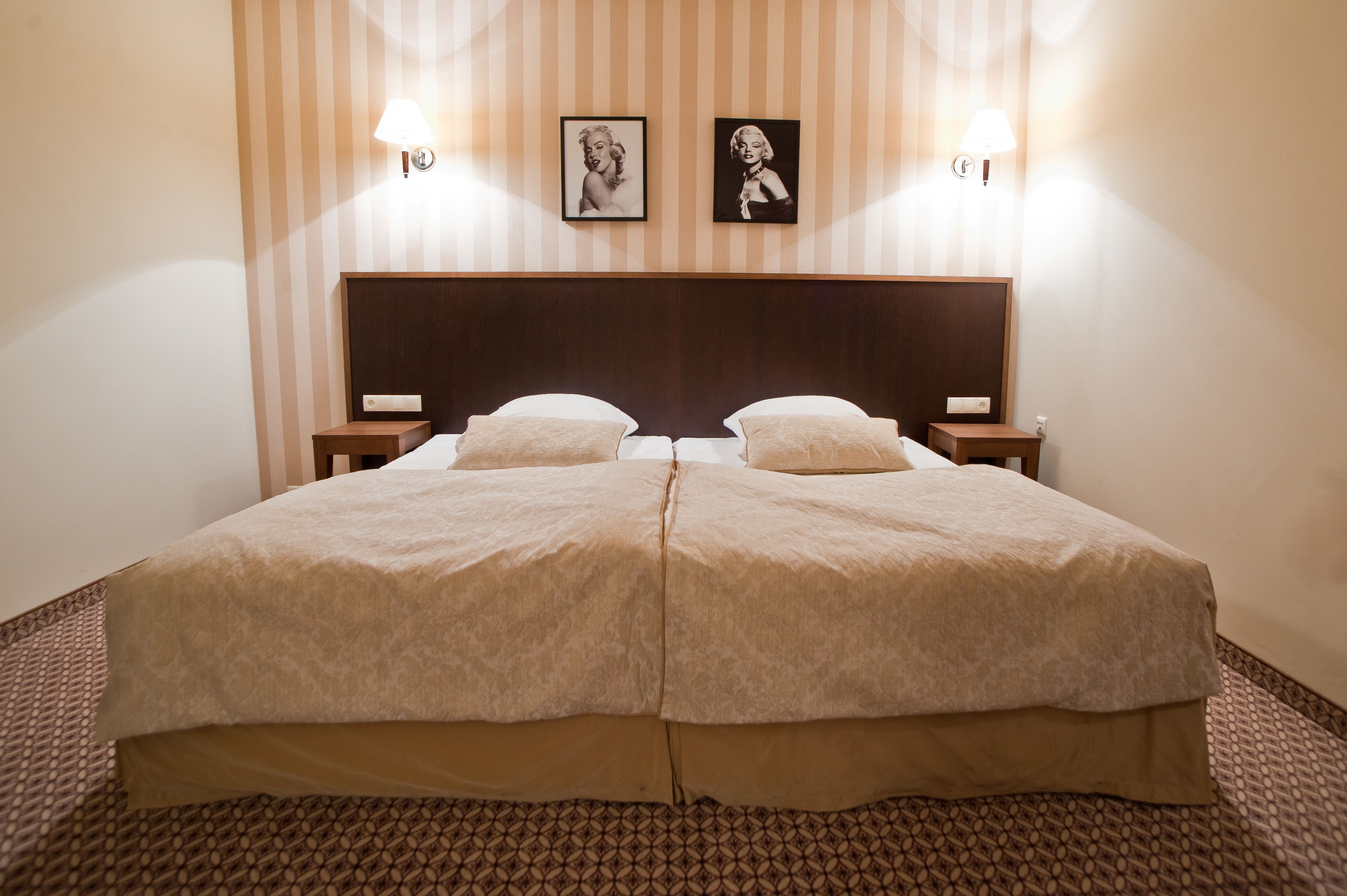 A double bed with a wooden headboard, two bedside tables, and two wall-mounted lamps.