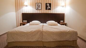 A double bed with a wooden headboard, two bedside tables, and two wall-mounted lamps.