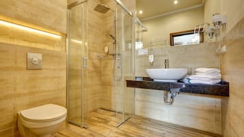 A modern bathroom with a glass-enclosed shower, a white toilet, and a vanity with a sink and towel rack.
