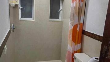 Un baño pequeño con un inodoro, un bote de basura verde y una cortina de ducha.