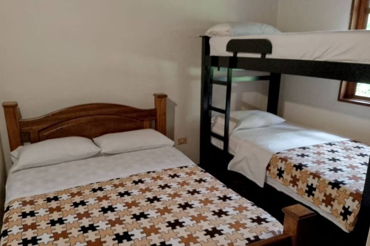 A room with a wooden bed, a bunk bed, and a patterned bedspread.