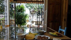 Un tavolo da pranzo con diversi piatti, una sedia e vista attraverso una finestra con inferriate.