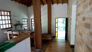 Una stanza con pavimento in legno, parete in mattoni e finestra vista su del verde.
