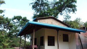 Una casa a un piano con un portico coperto, tetto in mattoni e un piccolo giardino.