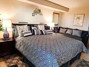 Un dormitorio ordenado con una cama grande, dos mesitas de noche y un tocador.