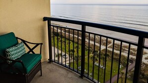 A balcony with a view of the ocean, a green chair, and a railing. - Boardwalk 932 (Myrtle Beach)