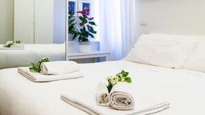 A hotel room with a bed, a mirror, a window with curtains, and a plant. - B&B Casetta Roma  (Rome)
