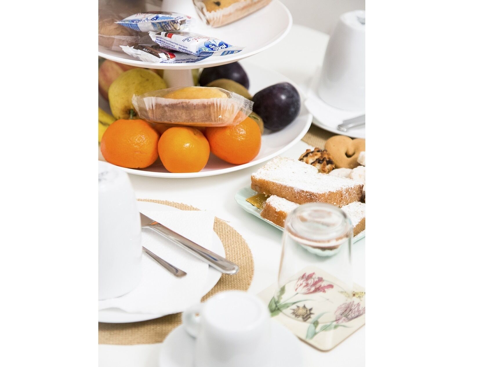 Ein Frühstückstisch mit einer Schale Orangen, einer Auswahl an Gebäck und einer Kaffeetasse.