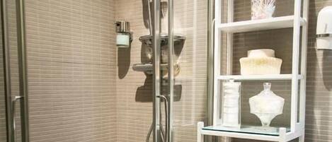 Ein modernes Badezimmer mit einer in Glas abgeschlossenen Dusche, einer weißen Fliesenwand und einer Glastrennwand mit Dekorationselementen.