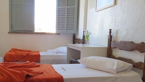 A hotel room with two beds, one with an orange blanket and the other with a white pillow. - Hotel Centenário (Juiz de Fora)