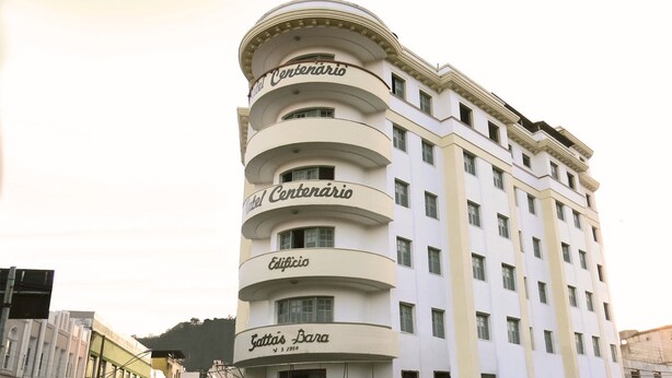 A multi-story hotel with a curved facade, featuring balconies and a classic architectural style. - Hotel Centenário (Juiz de Fora)