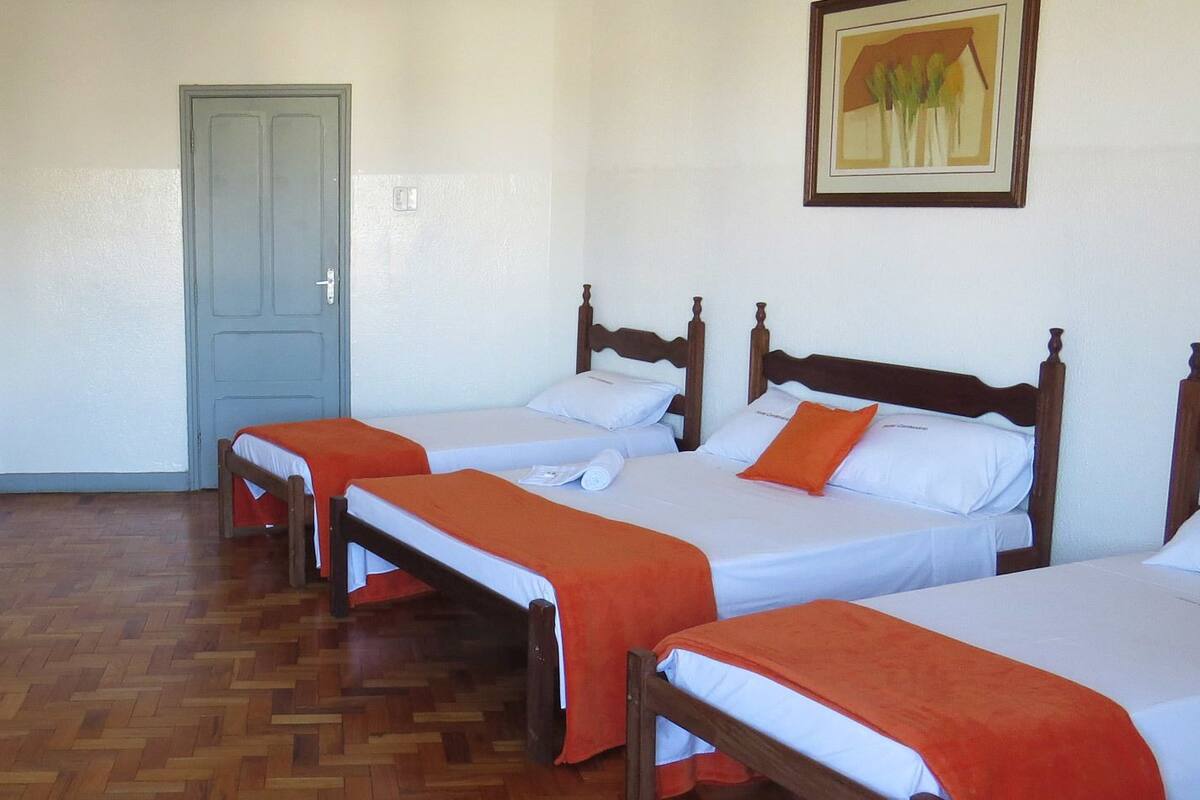 Une chambre avec trois lits simples, un bureau, une chaise et un petit réfrigérateur.