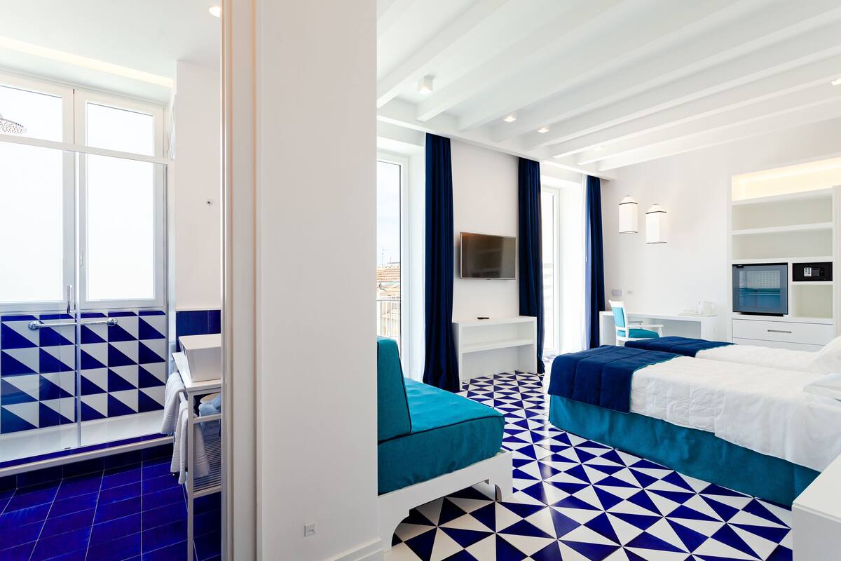 Une chambre d’hôtel avec une grande fenêtre, un lit, un bureau et une chaise.