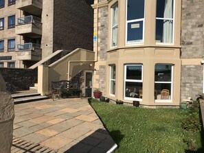 A multi-story building with a stone facade, a staircase leading to the entrance, and a small garden area with potted plants. - The Beaches Family B&B (Weston-super-Mare)