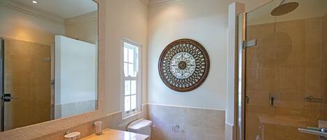 A bathroom with a large mirror, a sink, a toilet, and a glass shower enclosure.