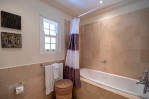 A bathroom with a bathtub, a window, and a shower curtain.