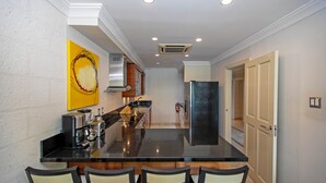 A modern kitchen with a central island, stainless steel appliances, and a yellow abstract painting on the wall. - Waterside 303 (Paynes Bay)