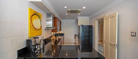 A modern kitchen with a central island, stainless steel appliances, and a yellow abstract painting on the wall.
